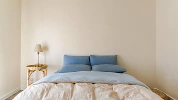A bedroom with a bed, a bedside lamp, and a small side table.