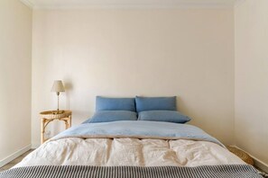 A bedroom with a bed, a bedside lamp, and a small side table. - Spacious Unley Home | Fast WiFi & Free Parking (Unley)