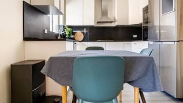 A compact kitchen with a dining table, chairs, and modern appliances.