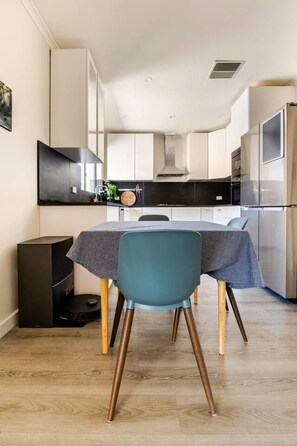 A compact kitchen with a dining table, chairs, and modern appliances. - Spacious Unley Home | Fast WiFi & Free Parking (Unley)
