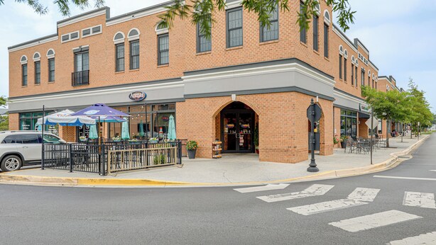 A brick building with a storefront, outdoor seating, and a crosswalk. - The Breeze at Lewes Condo w/ Pool | Bike to Beach! (Lewes)