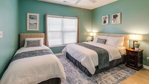 A bedroom with two beds, a ceiling fan, a window with blinds, and a nightstand with a lamp. - The Breeze at Lewes Condo w/ Pool | Bike to Beach! (Lewes)