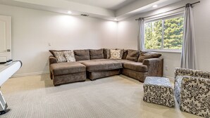 Una sala de estar con sofá modular, reposapiés y ventilador de techo.