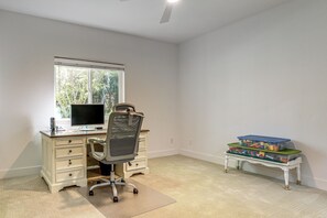 Una habitació amb escriptori, cadira, ordinador i una petita taula amb caixes d'emmagatzematge.