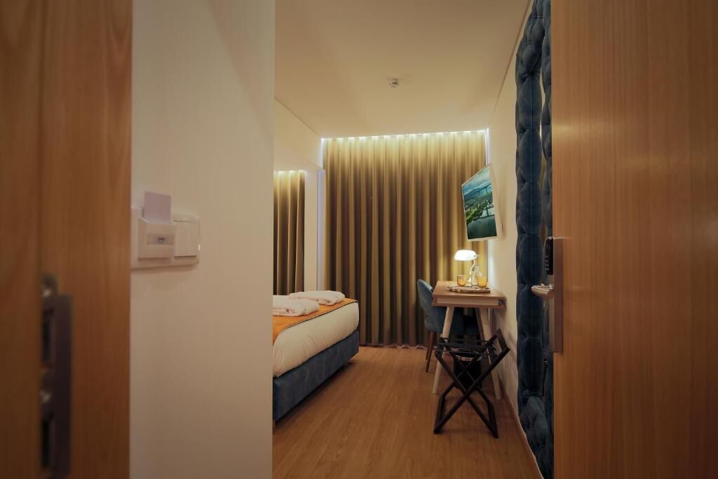 Een hotelkamer met een bed, een bureau, een stoel, een televisie en een gordijn.