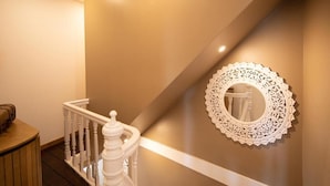 Una escalera con barandilla blanca y un espejo de pared decorativo.