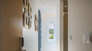 Un pasillo con piso de madera, una puerta a la izquierda y un ventanal al final.