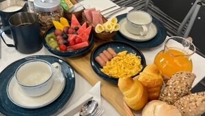 Una preparación para el desayuno con diferentes alimentos, una cafetera y un tazón de sopa.