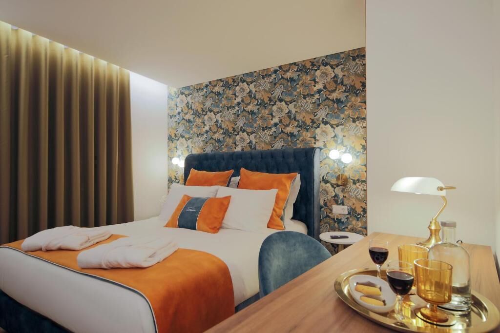 Ein Hotelzimmer mit einem Bett, einem Nachttisch mit Lampe sowie einem Tablett mit Gläsern und einer Flasche.