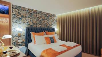 Ein Hotelzimmer mit einem großen Bett, einem Nachttisch mit Lampe und einer Wand mit Blumenmuster.