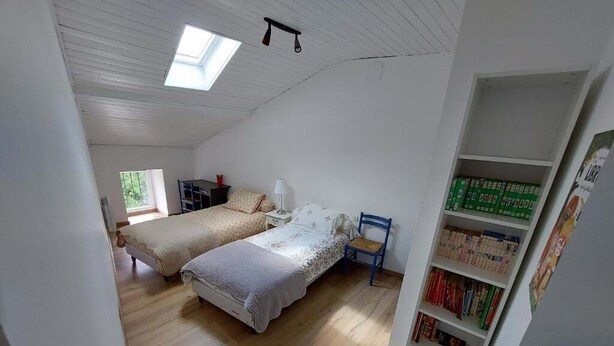 A bedroom with two beds, a skylight, a bookshelf, and a window. - Gite des Anglais proche de Poitiers (Marnay)