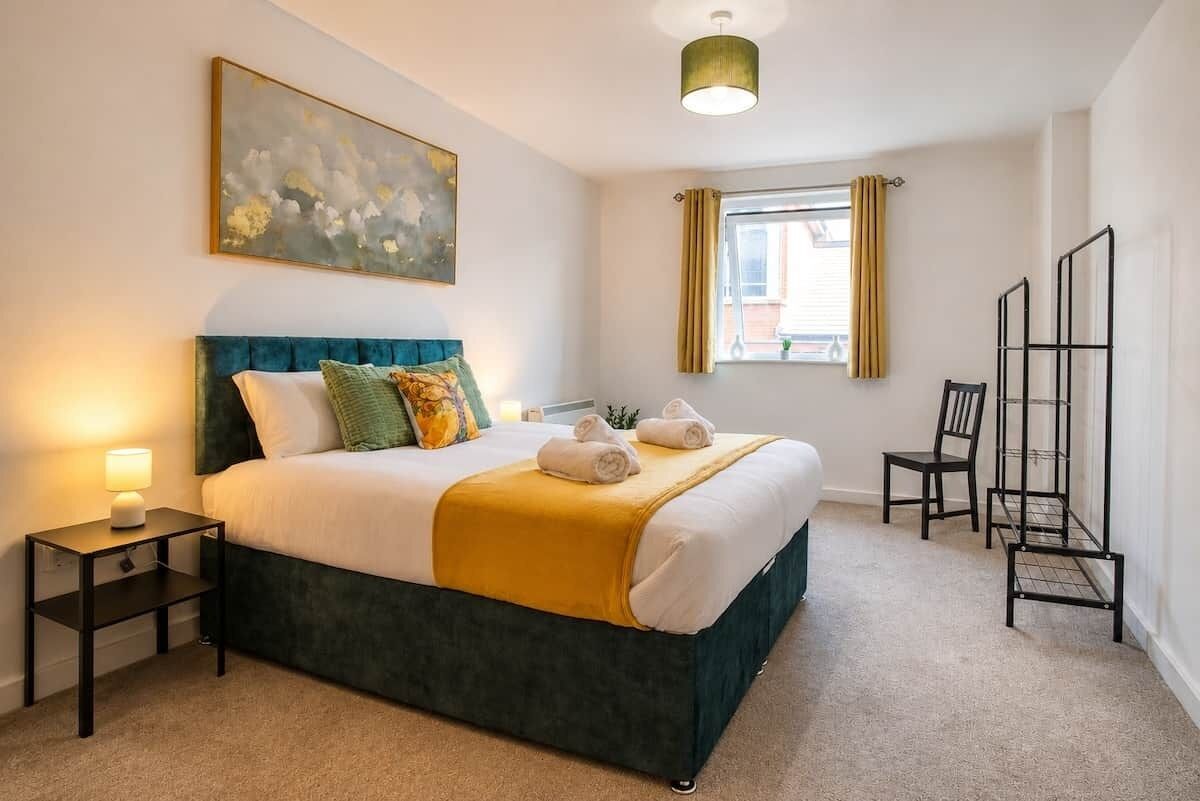 A neatly arranged bedroom with a bed, bedside table, lamp, and a window with curtains.