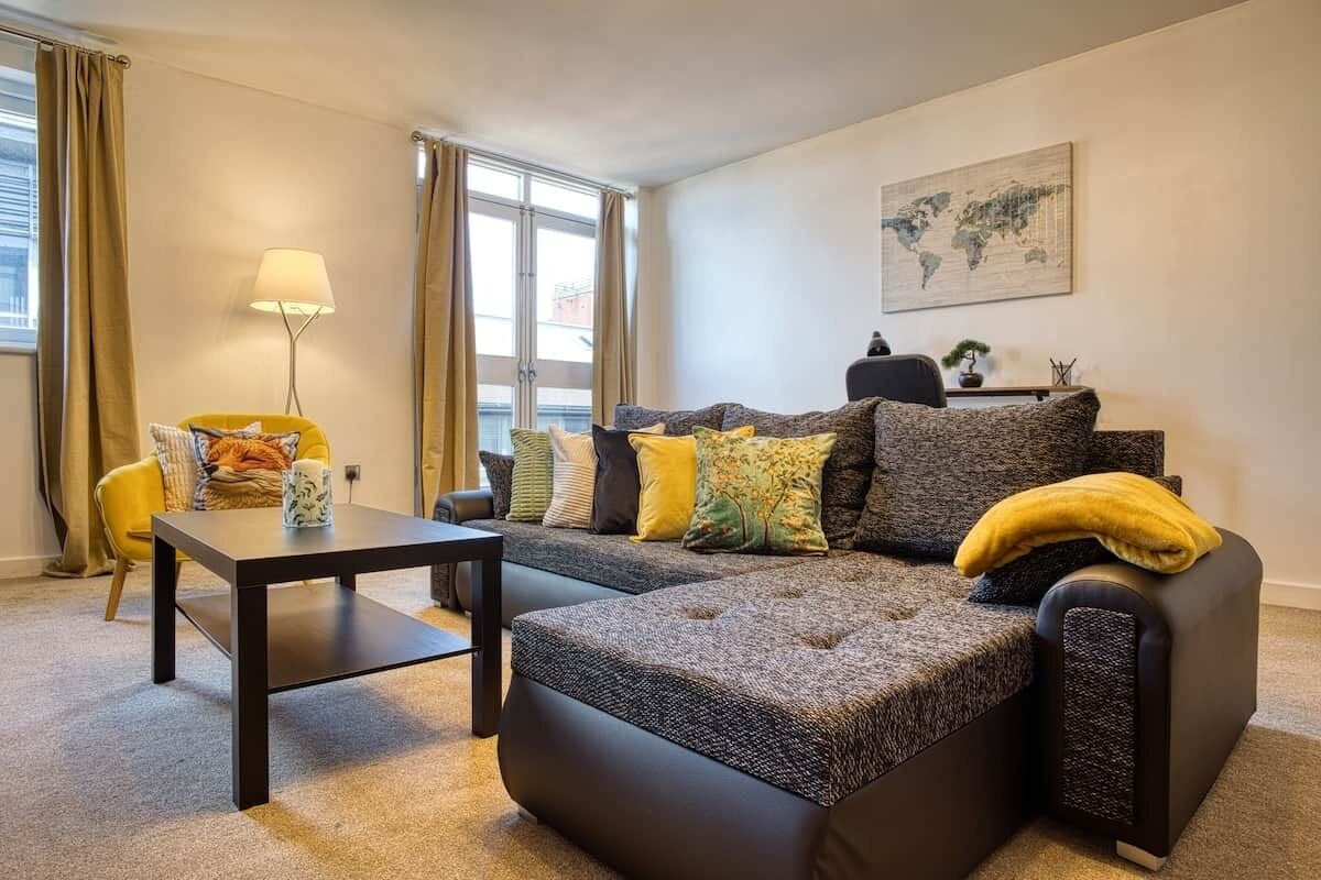 Ein modernes Wohnzimmer mit einem Ecksofa, einem kleinen Tisch und einer Lampe.