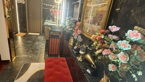 A marble-floored lobby with a red bench, a large framed mirror, and a floral arrangement. - MM HOUSE - METRO Q1 (Ho Chi Minh City)
