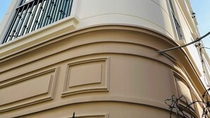 A corner building with a curved facade, large windows, and a balcony with a railing. - MM HOUSE - METRO Q1 (Ho Chi Minh City)