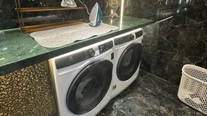 Uma área de lavanderia moderna com máquina de lavar, varal e uma planta decorativa.