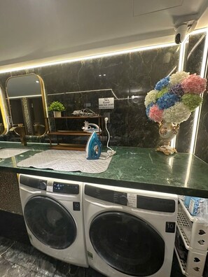 A hotel reception area with a marble counter, a washing machine, and a decorative vase with flowers. - MM HOUSE - METRO Q1 (Ho Chi Minh City)