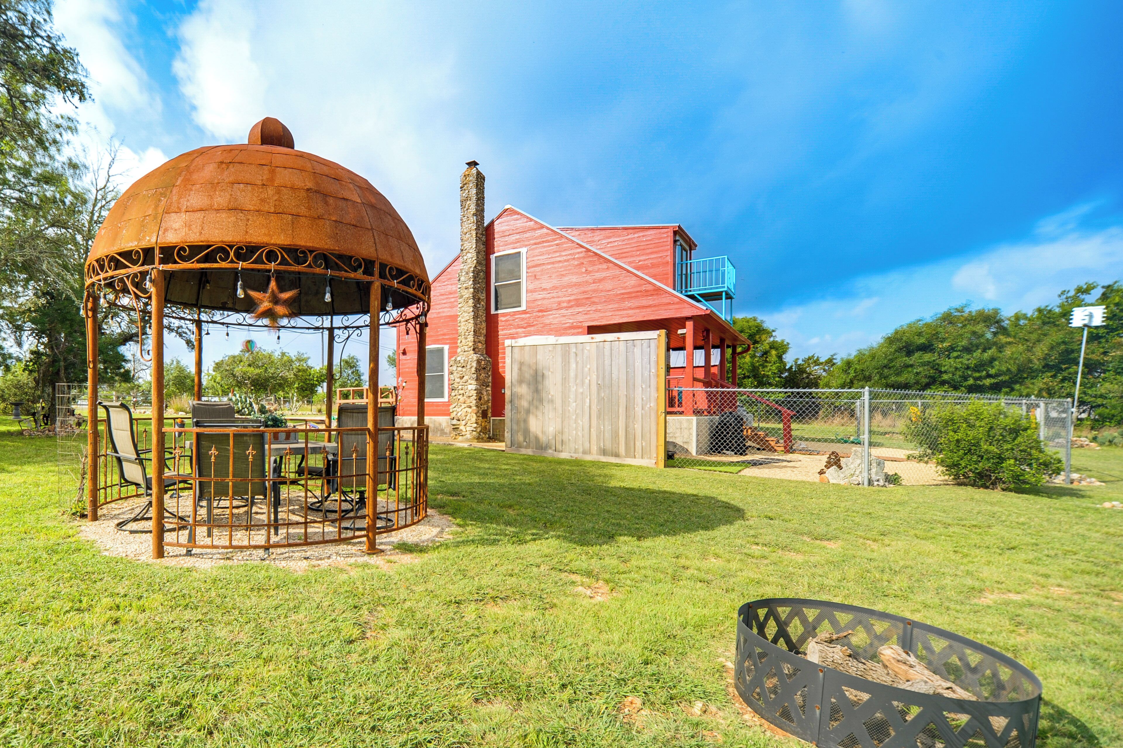 A gazebo with a star decoration, a red building with a wooden door, and a fenced yard.