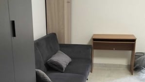 Ett rum med en grå soffa, ett träbord och en garderob.