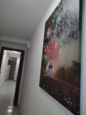 Een gang met een groot schilderij van vuurwerk en een menigte mensen.