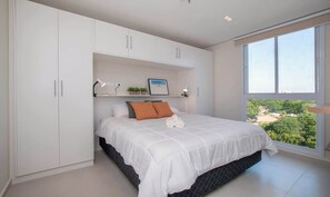 A bedroom with a bed, white wardrobe, and a large window. - Corporate Stays First Living - 605 (Asunción)