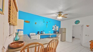 Una cocina con pared azul, armarios blancos, estufa y ventilador de techo.