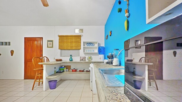 Una cocina con estufa integrada, un lavamanos y una ventana con persianas.