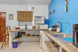 Een keuken met een spoelbak, fornuis en diverse keukenbenodigdheden.