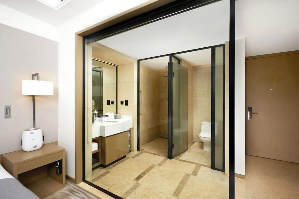 Un baño de hotel moderno con ducha de vidrio, lavamanos e inodoro.