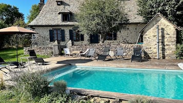 Una casa de pedra amb piscina, zona de seients a l'aire lliure i jardí.