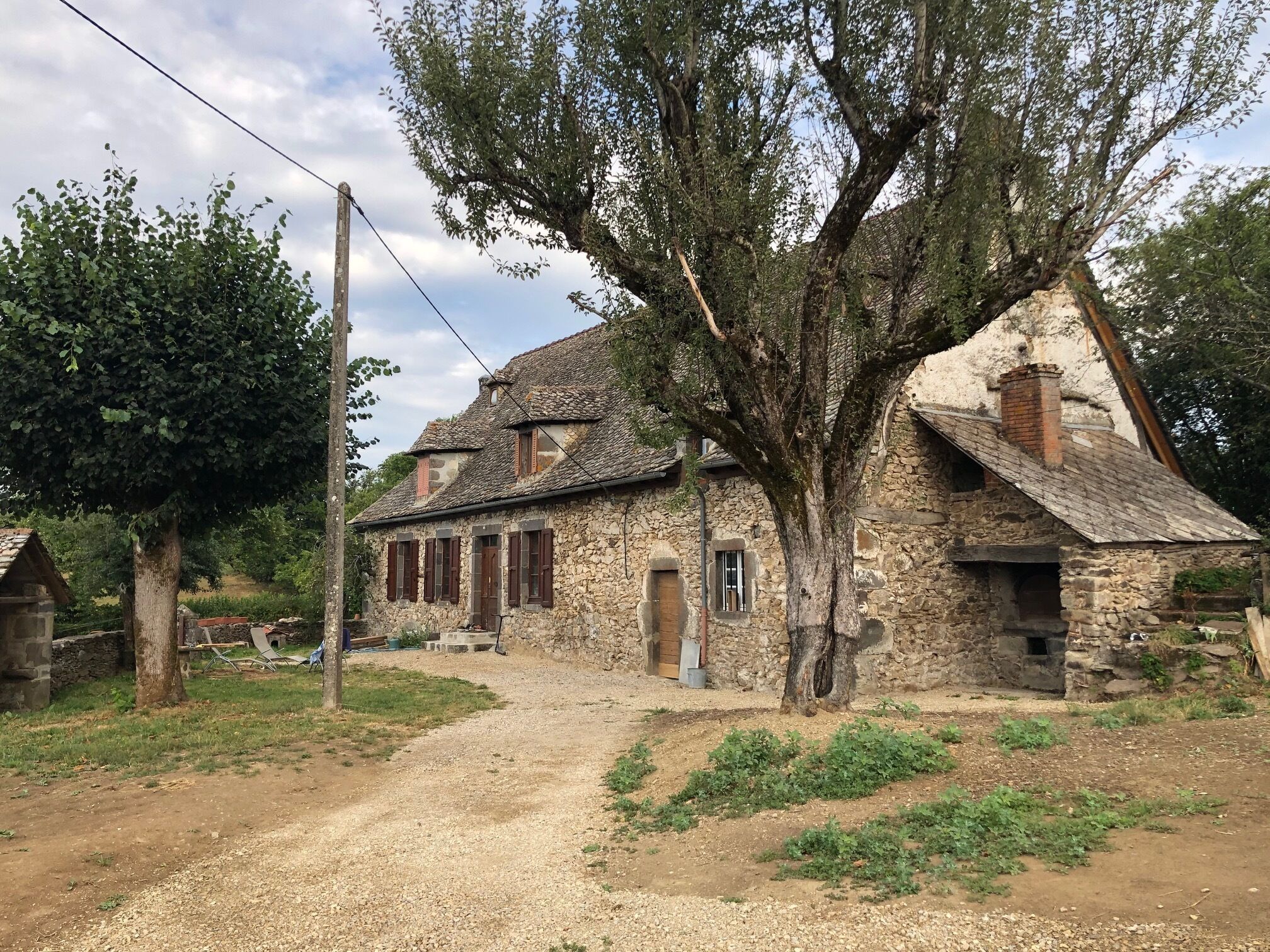 Un edificio rústico de piedra con un sendero de tierra que lo lleva hasta él, rodeado de vegetación.