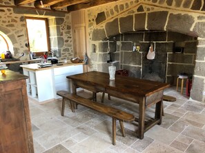 Eine rustikale Küche mit Steinwand, Holztisch und Bank.