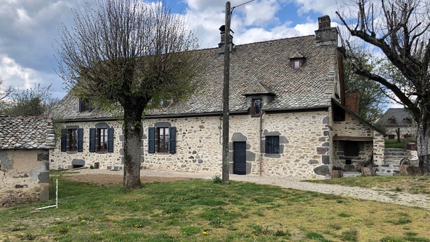 A stone building with a sloped roof, a small window, and a door. - Large Auvergne-style house with a pool, pétanque court, and bread oven (Saint-Martin-Cantalès)
