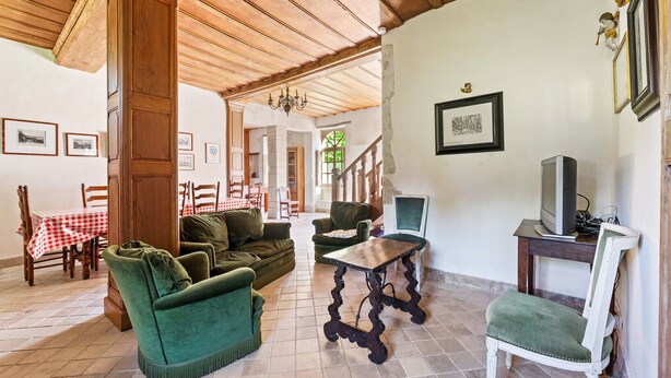A room with a wooden ceiling, green upholstered furniture, a wooden table, and a television on a stand. - Holiday Home in Le Manoir with Jacuzzi in summer (Le Manoir)