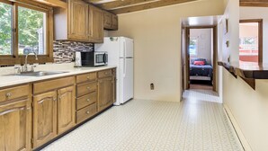 Una cocina con armarios de madera, un refrigerador blanco, un microondas y un lavamanos.