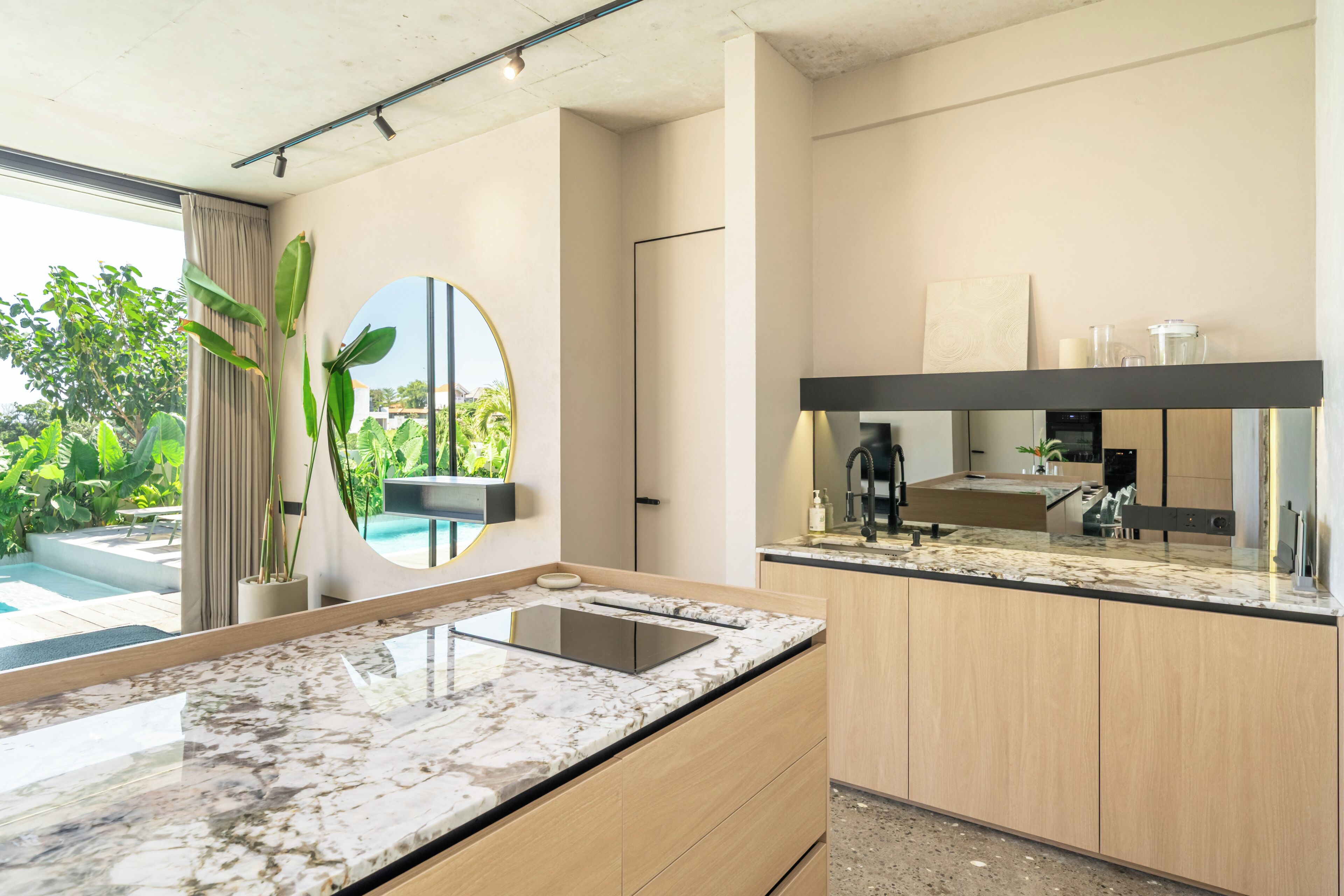 Una cocina moderna con encimeras de mármol, armarios de madera y un espejo grande.