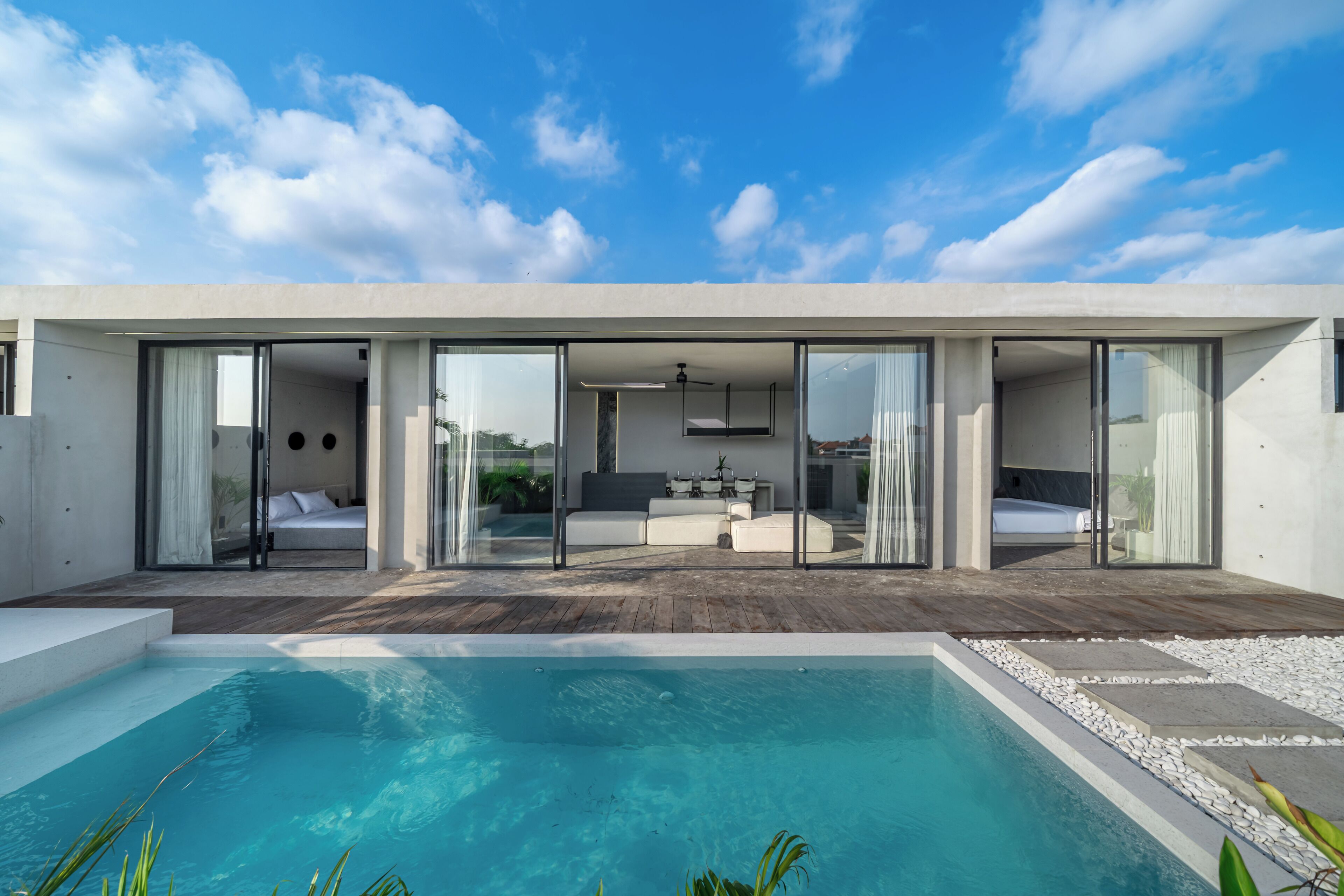 Une maison moderne dotée d’une piscine, de grandes portes vitrées et offrant une vue sur le ciel.
