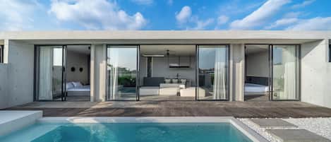 Una casa moderna con piscina, puertas de cristal grandes y vistas al cielo.