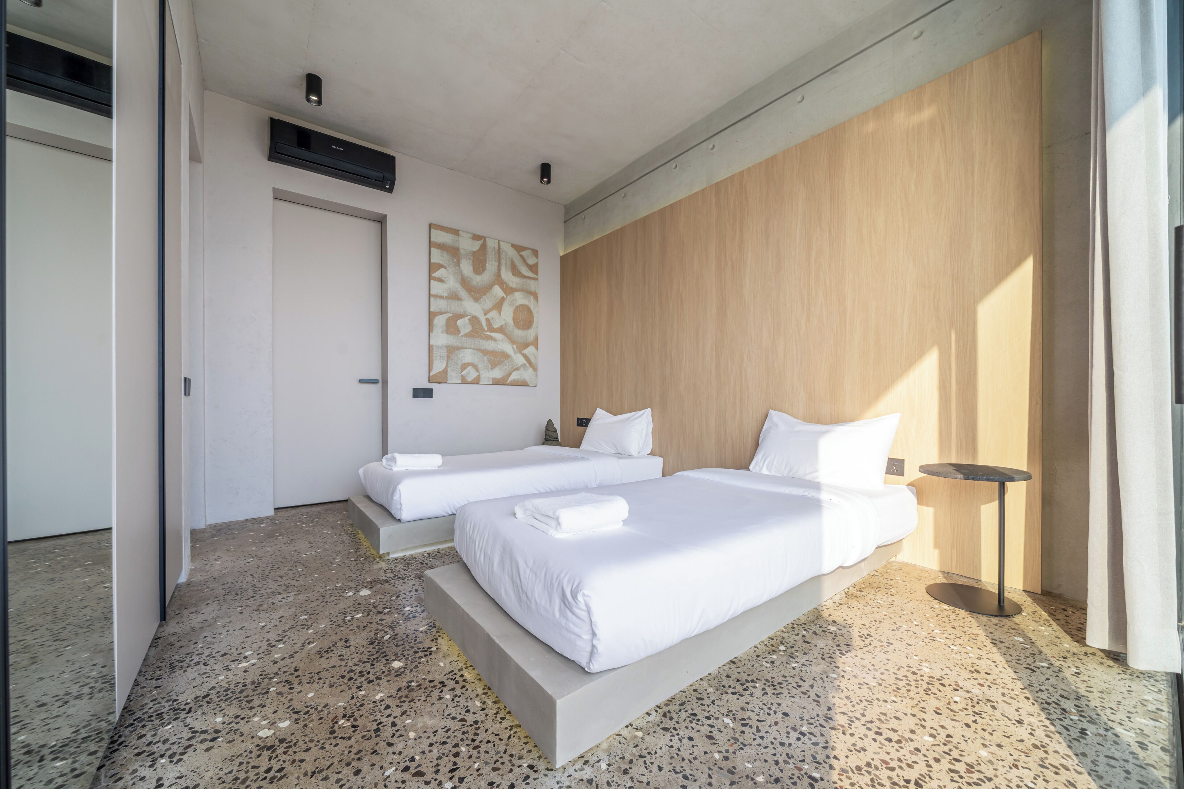 Ein Hotelzimmer mit zwei Betten, einer Holzwand, einem Gemälde und einem kleinen Tisch.