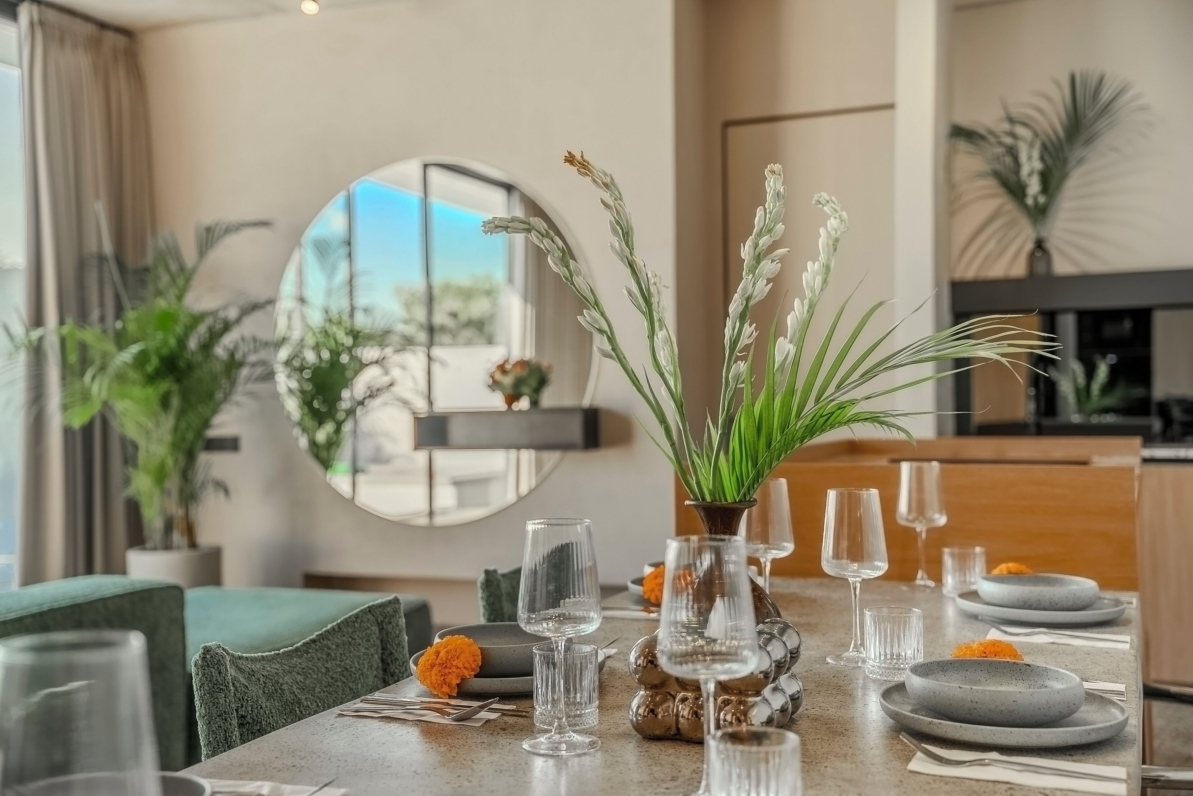 Una mesa de comedor con platos, vasos y una planta en maceta.