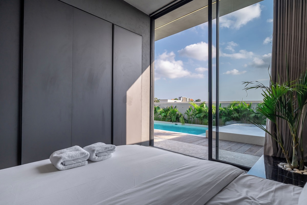 Un dormitorio moderno con un ventanal grande, una cama con ropa de cama blanca y vista a una piscina.