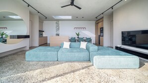 Una sala moderna con un sofá seccional, un comedor y una cocina.