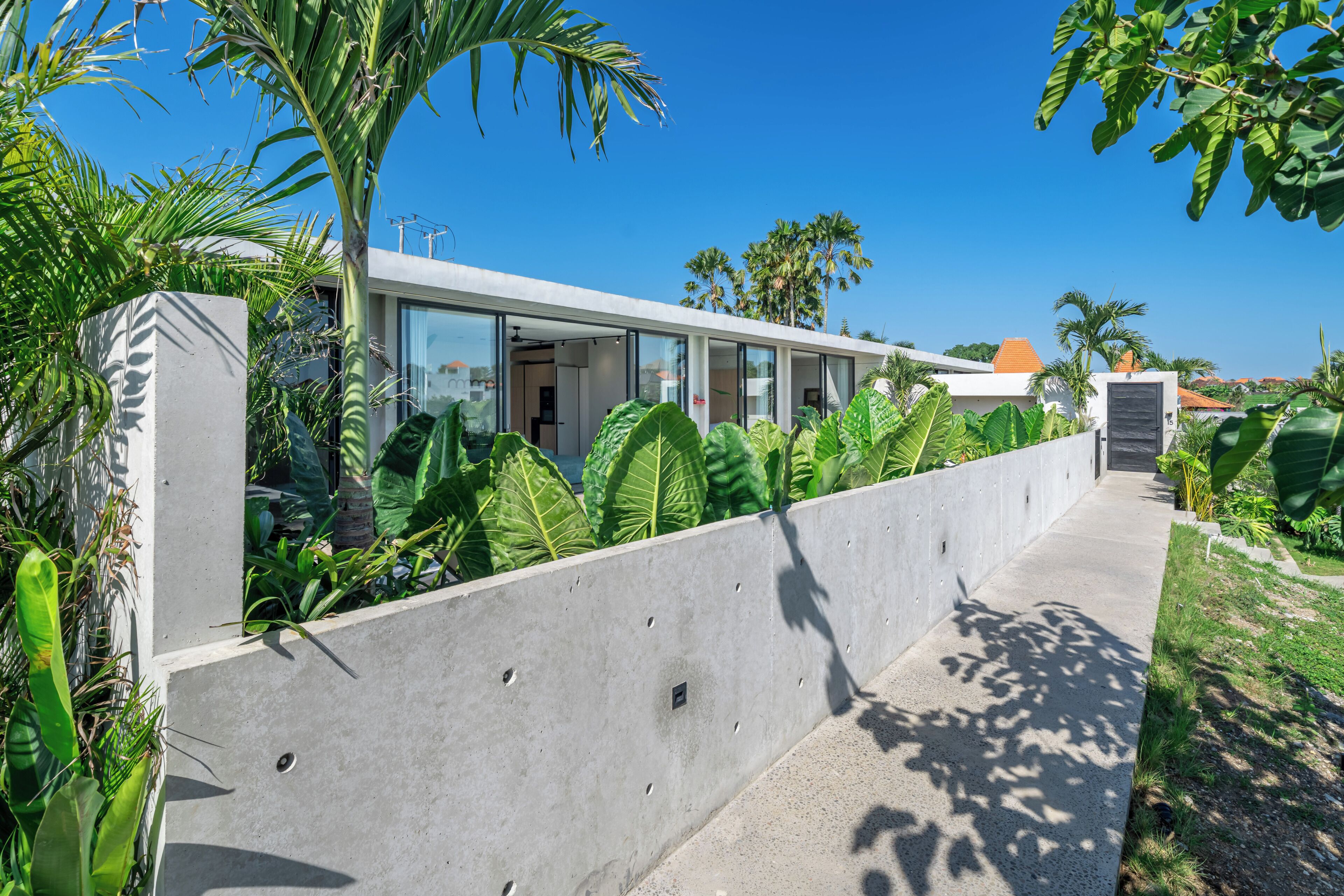 A modern building with a concrete facade, large windows, and a pathway leading to the entrance.