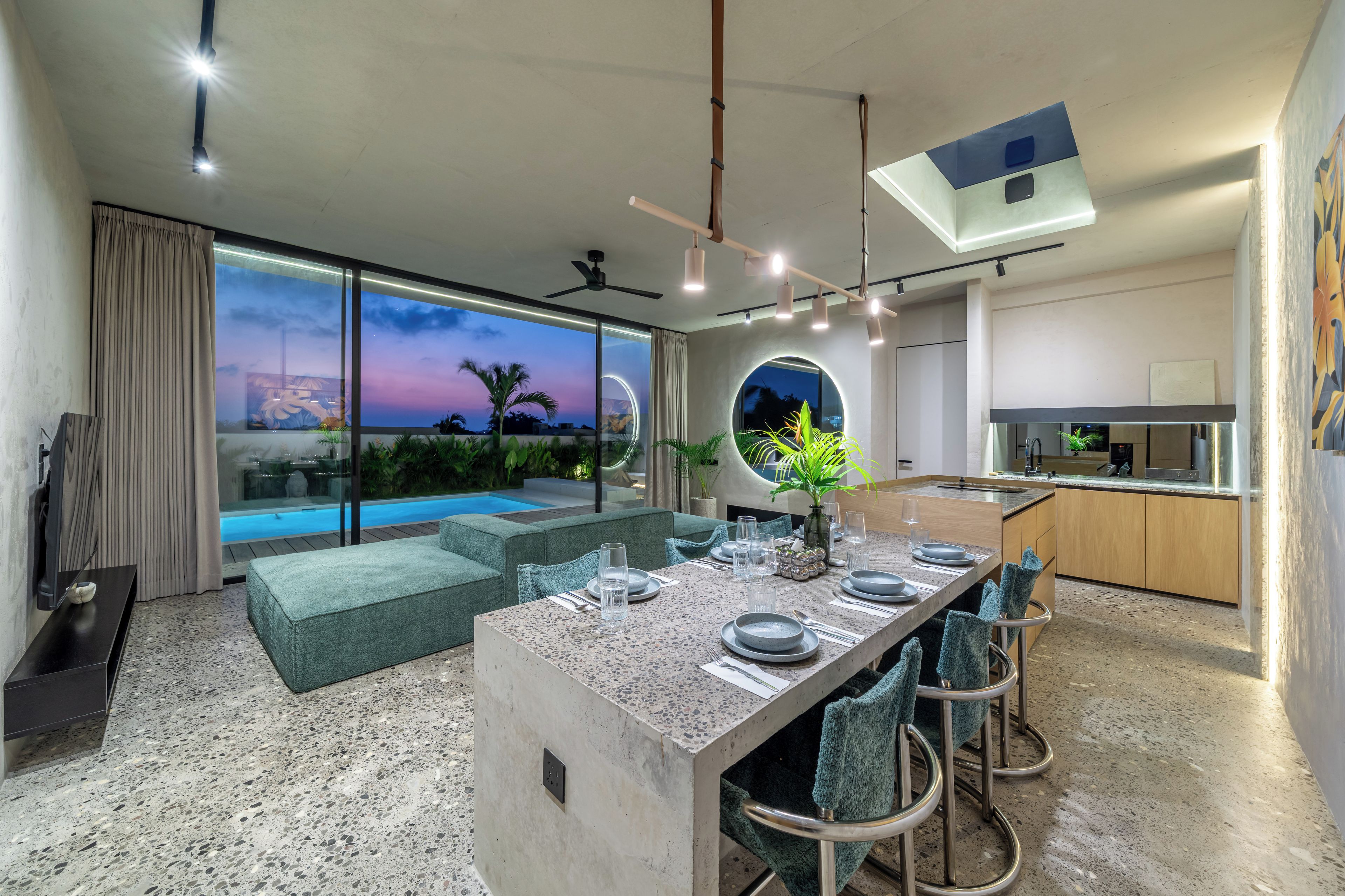 A modern interior with a dining area, kitchen, and a view of a swimming pool.