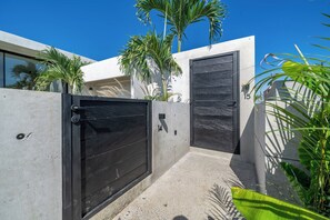 A modern house with two black doors, a concrete wall, and a small concrete patio. - Predmet Cascade Bali (Tabanan)