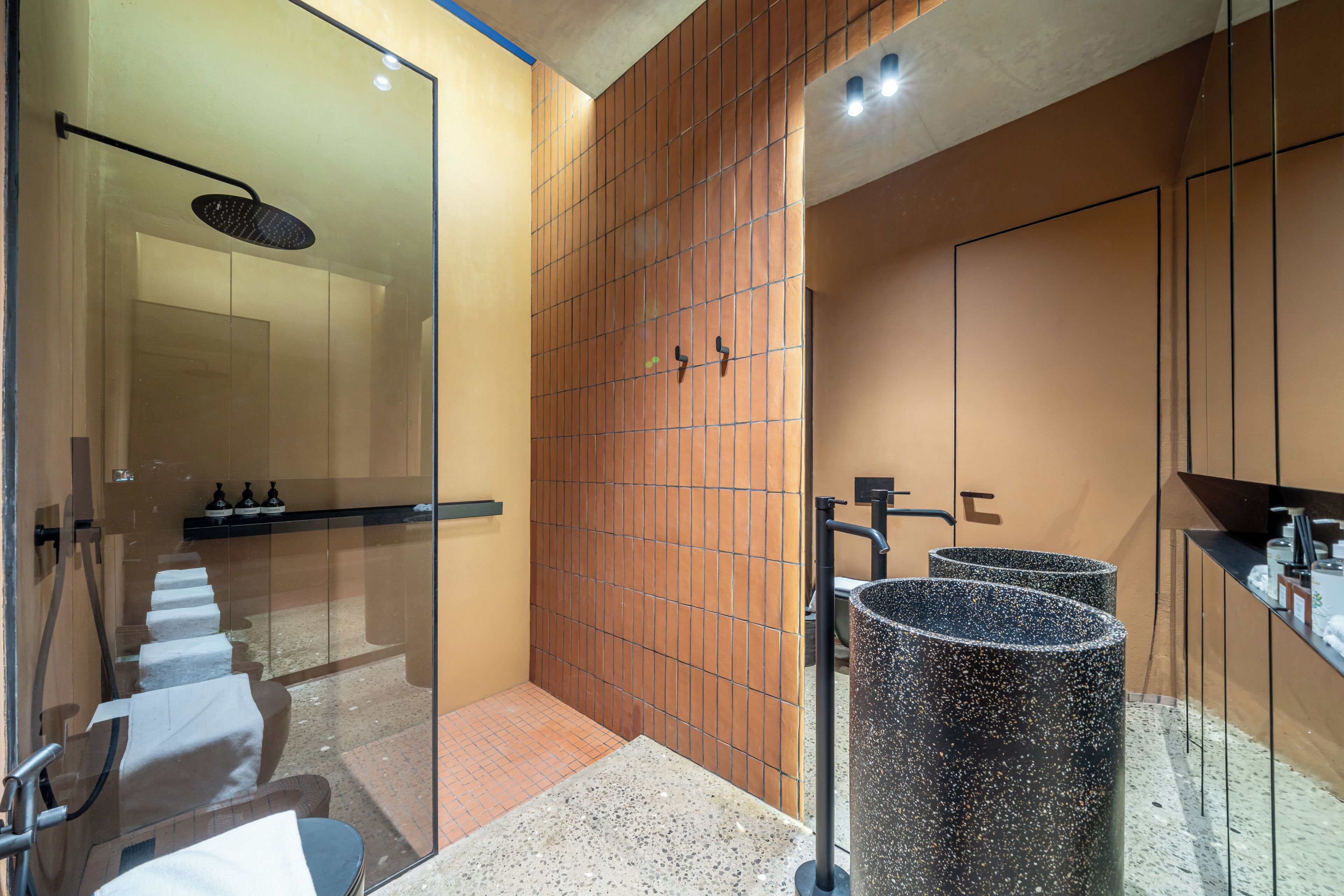 Un baño moderno con cabina de ducha de vidrio, pared con azulejos y lavamanos de porcelana veteada.