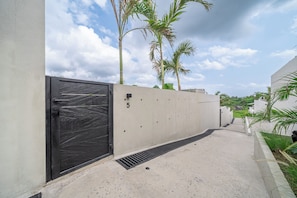 A gated entrance with a concrete wall, a metal door, and a number '5' on the wall.