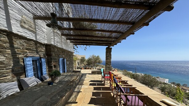A stone building with a terrace overlooking the sea, featuring outdoor seating and a pergola. - Scalinata Tinos Sophisticated Living (Tinos)
