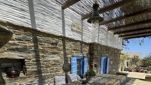 A stone patio with outdoor seating, a stone wall, and a blue door. - Scalinata Tinos Sophisticated Living (Tinos)