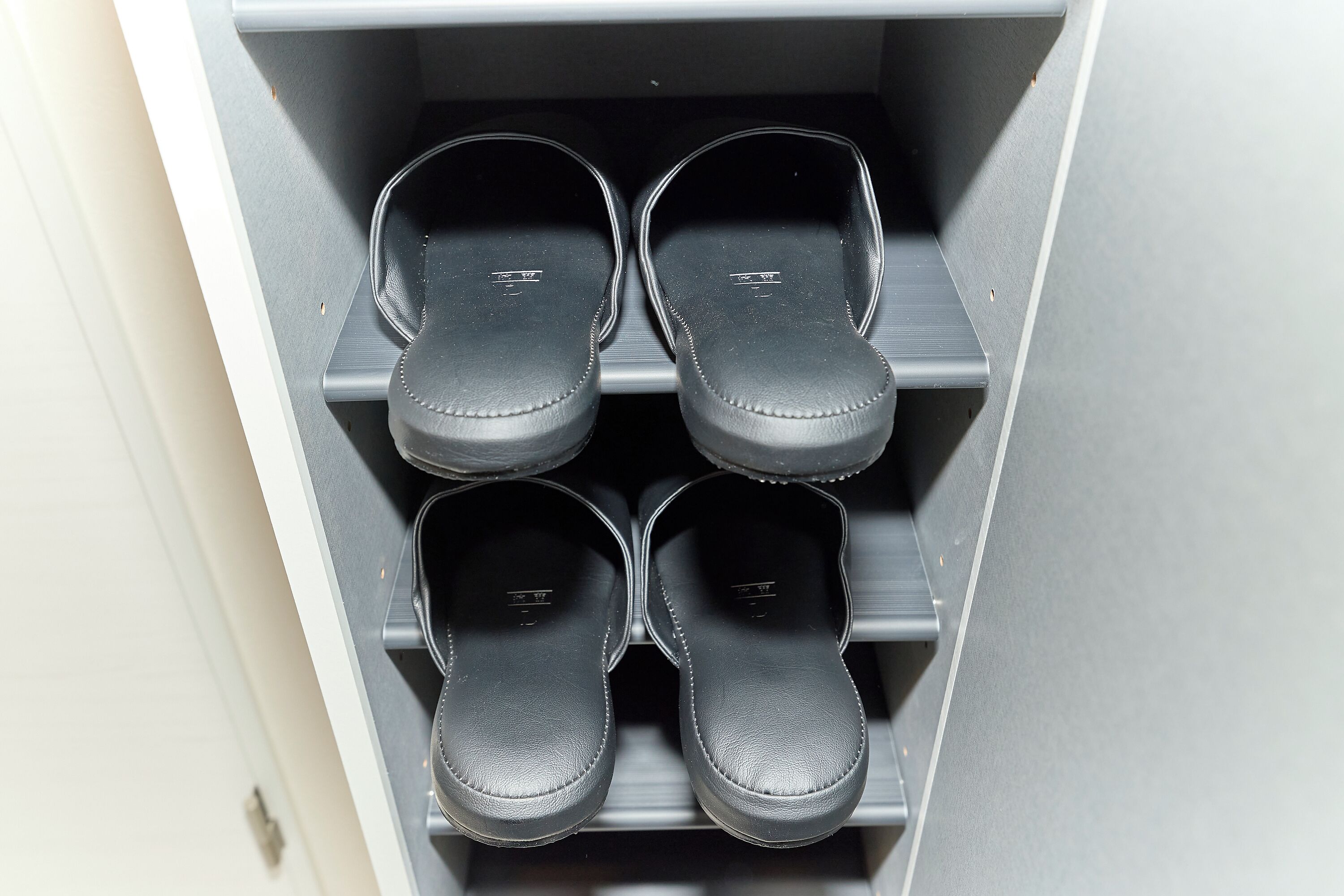 A shoe storage unit with four pairs of black shoes.